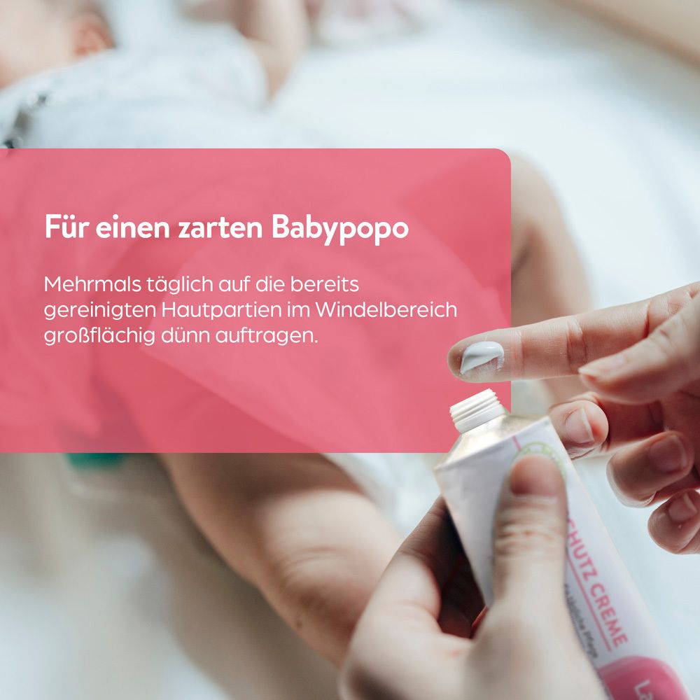 Hände tragen Lasepton Baby Schutz-Creme auf die Haut eines Babys im Windelbereich auf.