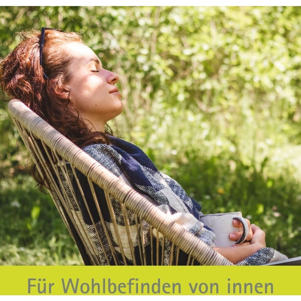 Frau entspannt in einem Stuhl im Garten. Text: Für Wohlbefinden von innen.