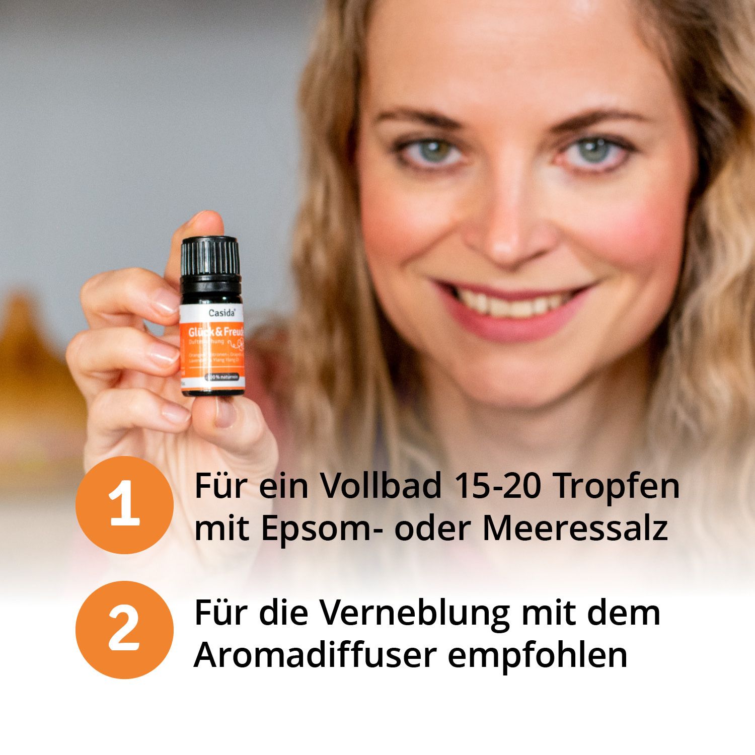 Femme tenant un petit flacon "Casida Glück & Freude". Instructions : 15-20 gouttes pour bain complet, ou pour diffuseur.