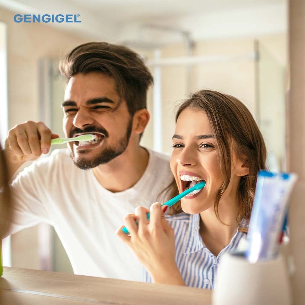 Couple se brossant les dents. Brosses à dents et dentifrice dans la salle de bain. Inscription GENGIGEL®.