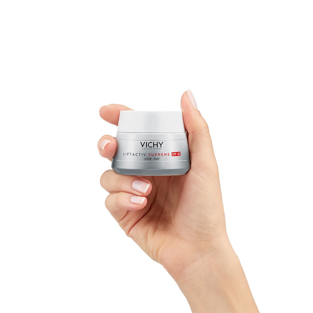 Main tenant un pot de Vichy LIFTACTIV SUPREME LSF 30. Contenant gris, couvercle blanc, indication LSF 30 rouge.