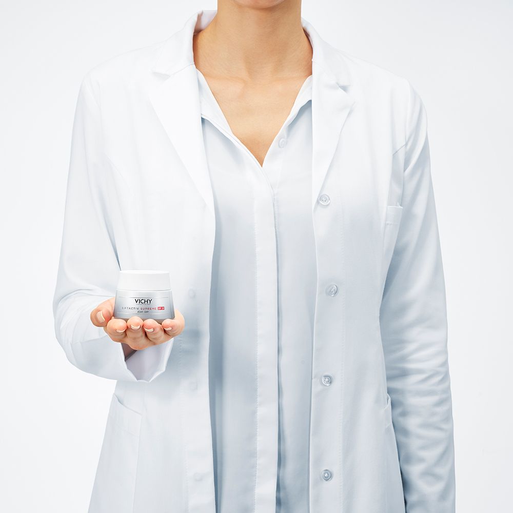 Femme en blouse blanche tenant un pot de Vichy LIFTACTIV SUPREME LSF 30.