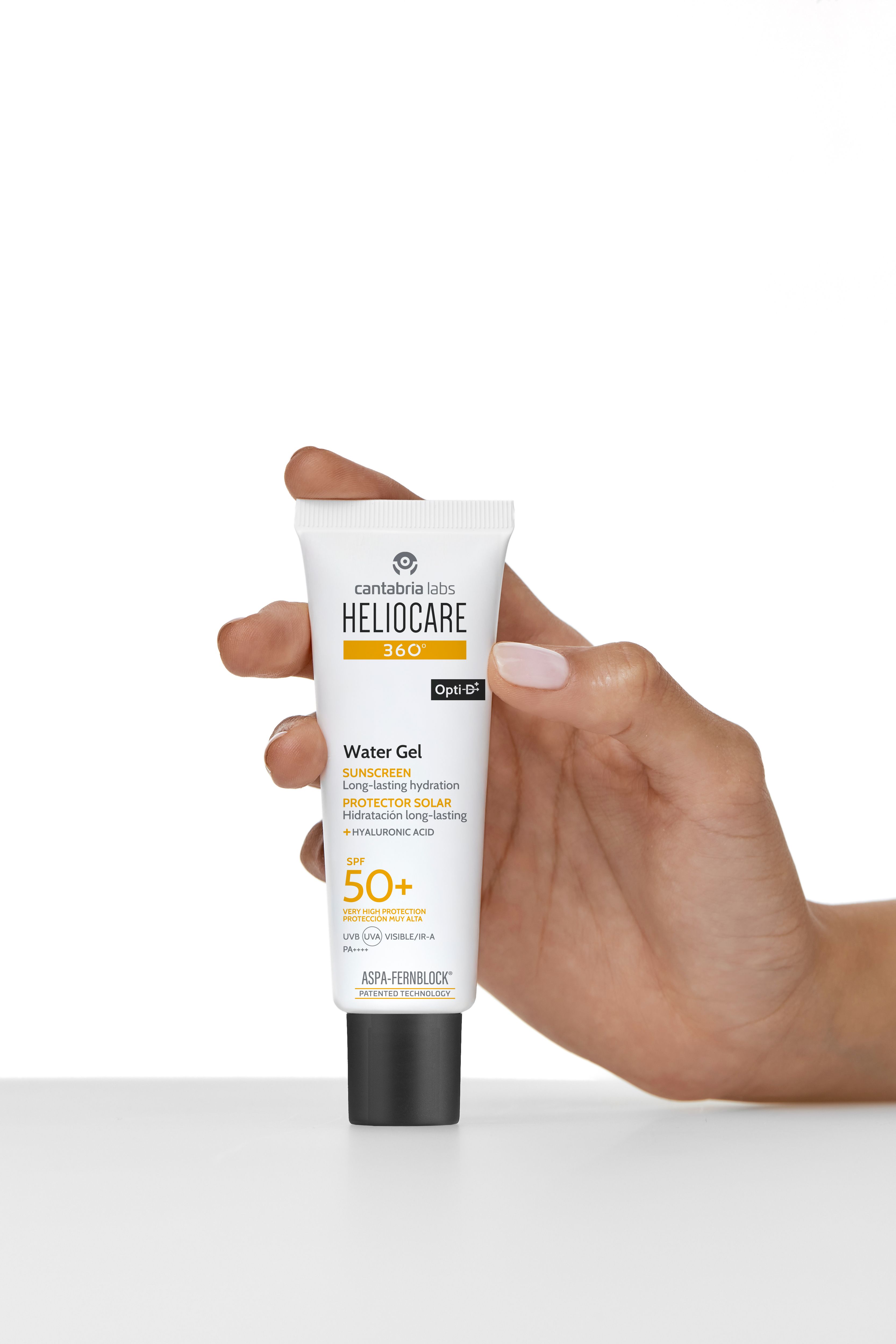 Tube blanc tenu dans une main. Inscription: HELIOCARE 360° Water Gel SPF 50+. Bouchon noir. Opti-D®.