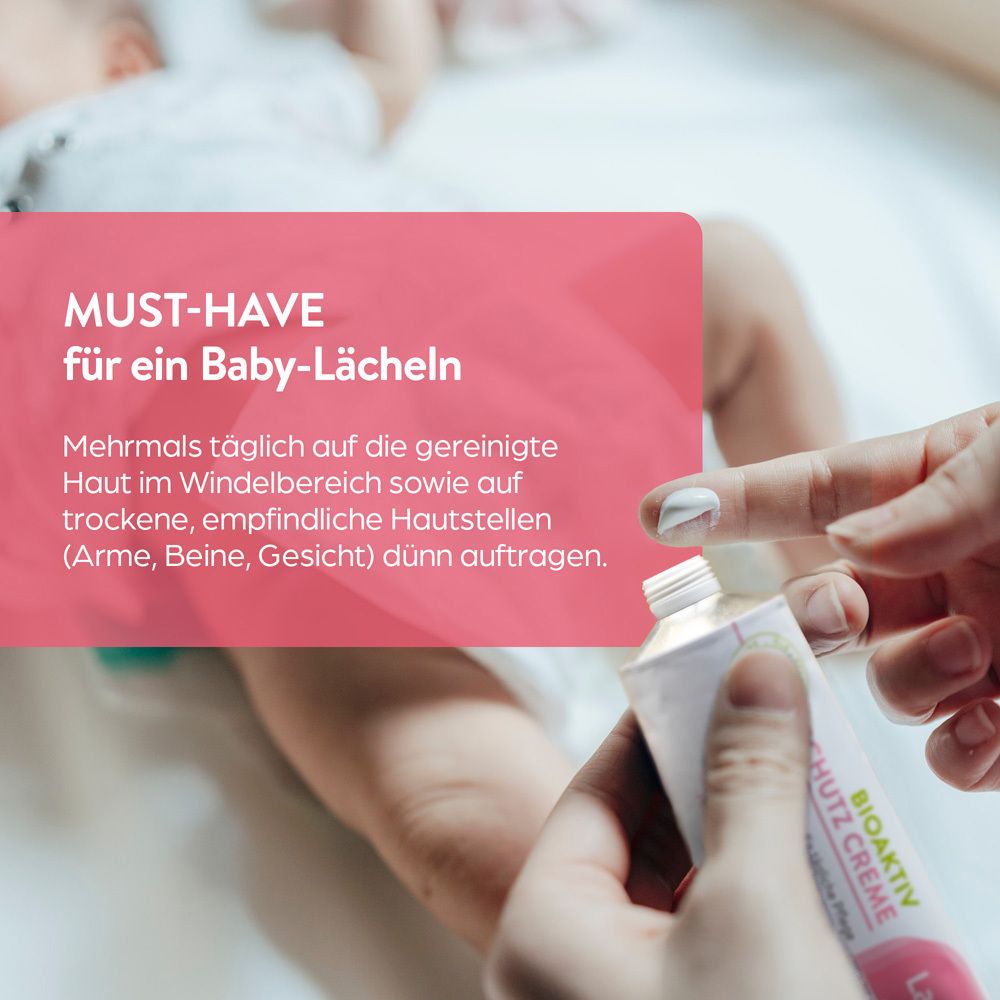 Eine Hand öffnet eine Tube Lasepton Baby Schutz Creme über einem Baby.