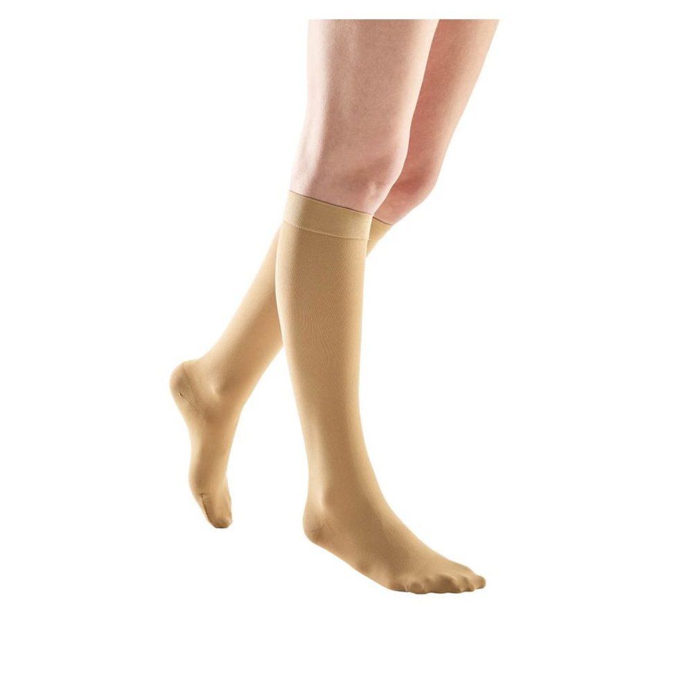 Bas de compression beiges. Les bas montent jusqu'au genou.