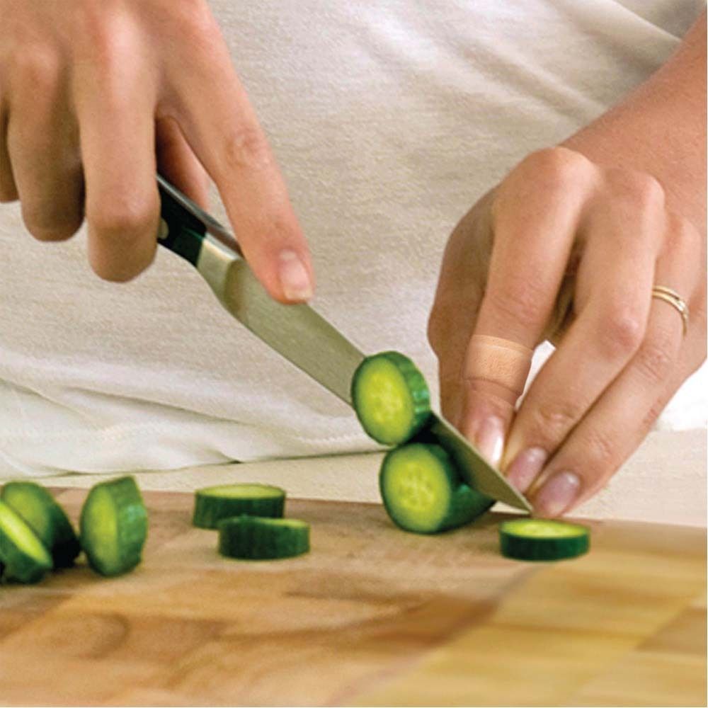 Person schneidet Gurken mit Messer. Ein Pflaster am Finger.