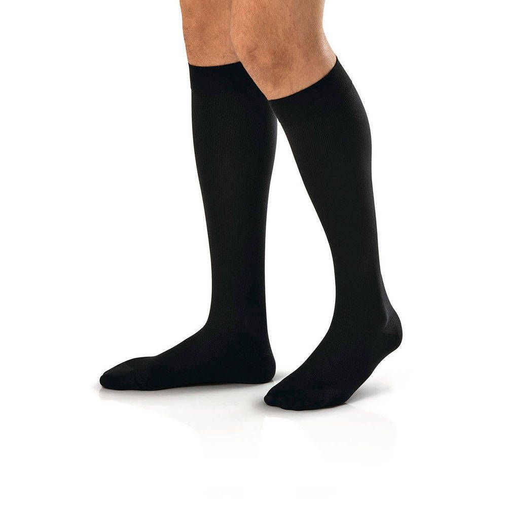 Schwarze Kompressionsstrümpfe am Bein einer Person. Die Strümpfe reichen bis zum Knie.