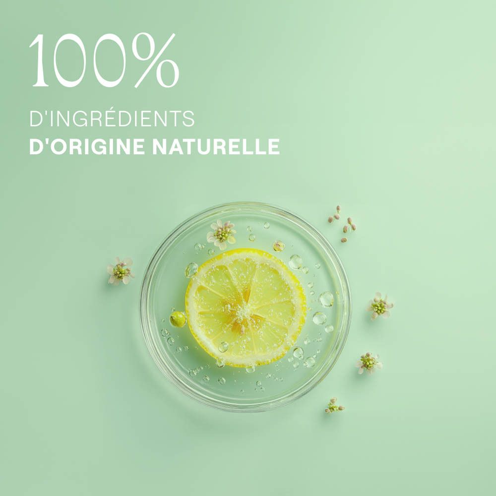 Image d'un bol transparent avec une tranche de citron, des fleurs et des gouttes d'eau. Texte: 100% D'INGRÉDIENTS D'ORIGINE NATURELLE.