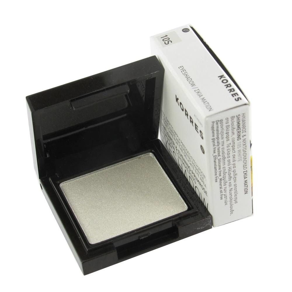 Offener Lidschattenbehälter mit weißem Lidschatten. Daneben eine weiße Verpackung mit Text. Schwarzer Behälter.