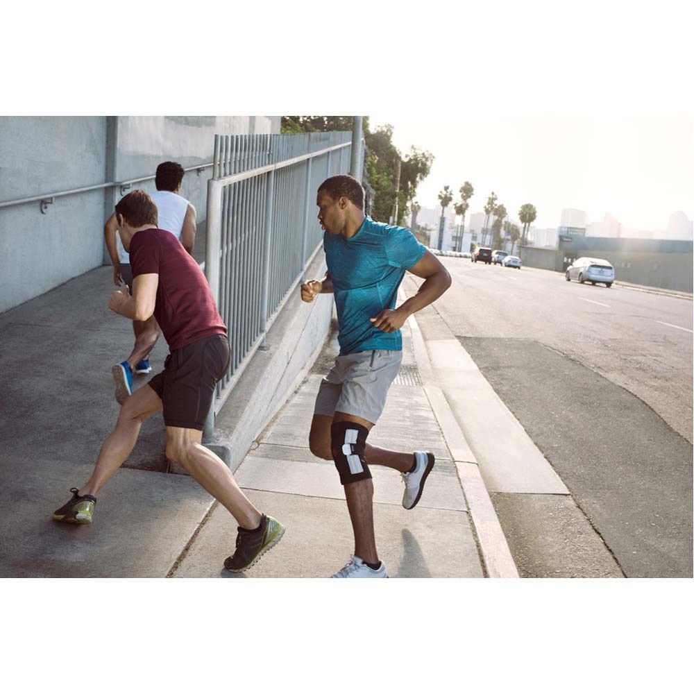 Kniebandage. Graue Bandage mit weißen Elementen. Auf einem weißen Bein. Rückseite der Verpackung.