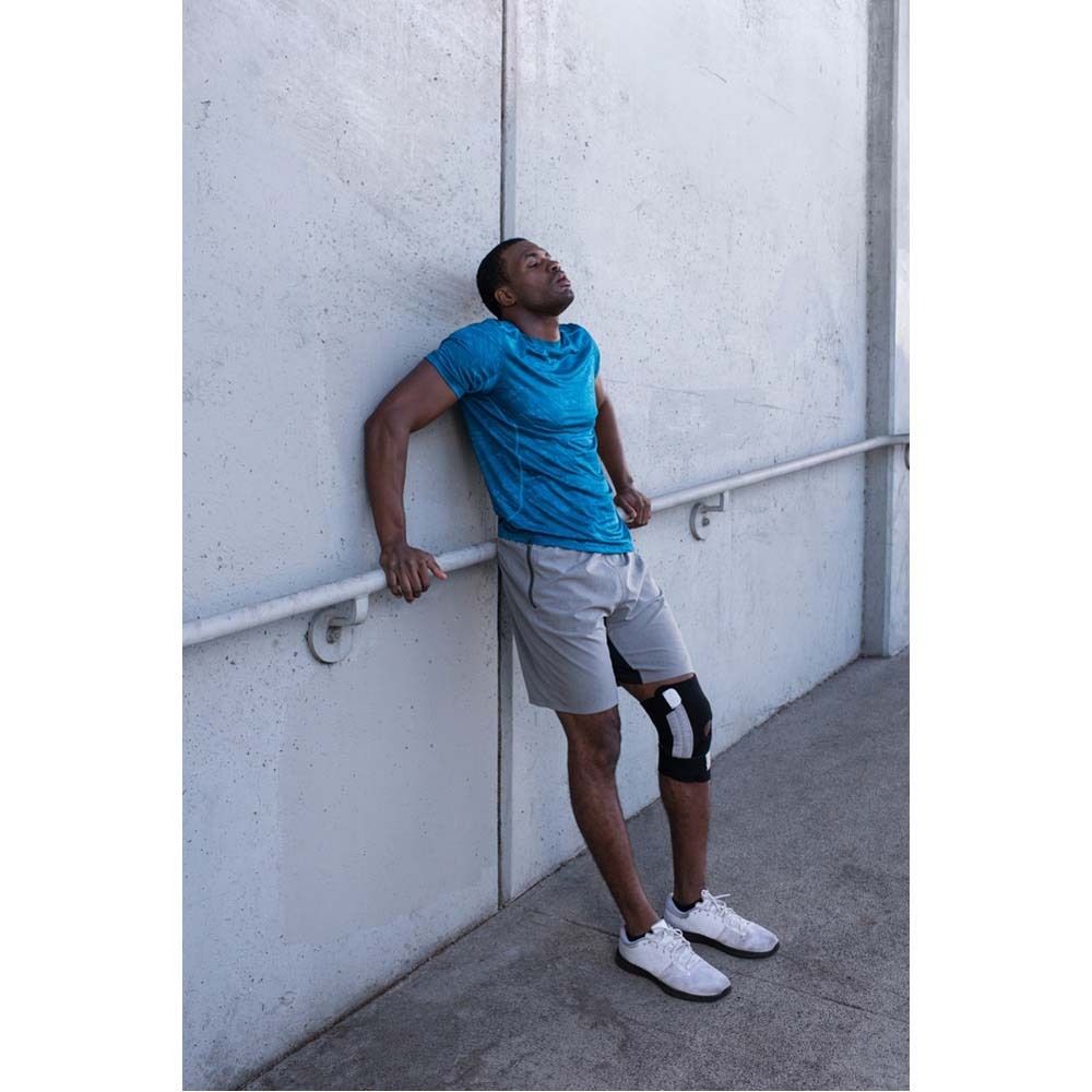 Kniebandage. Schwarze und graue Bandage am Bein einer Person. Verpackung mit Produktabbildung und Logo.