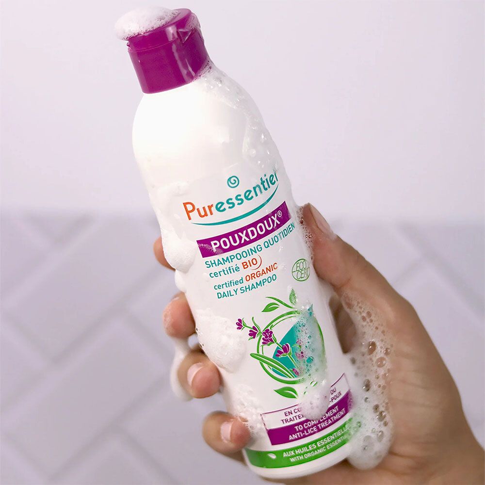 Flasche mit lila Verschluss, mit Schaum bedeckt. Aufschrift: Puressentiel Poudoux® Shampoo.