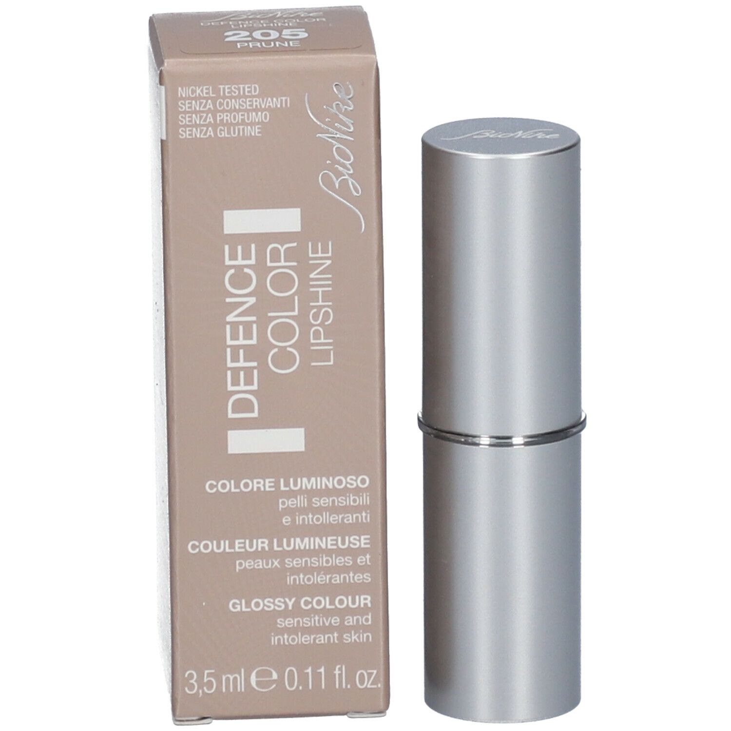 Rouge à lèvres en étui argenté, à côté d'un emballage. Sur l'emballage : nom du produit, couleur, marque.