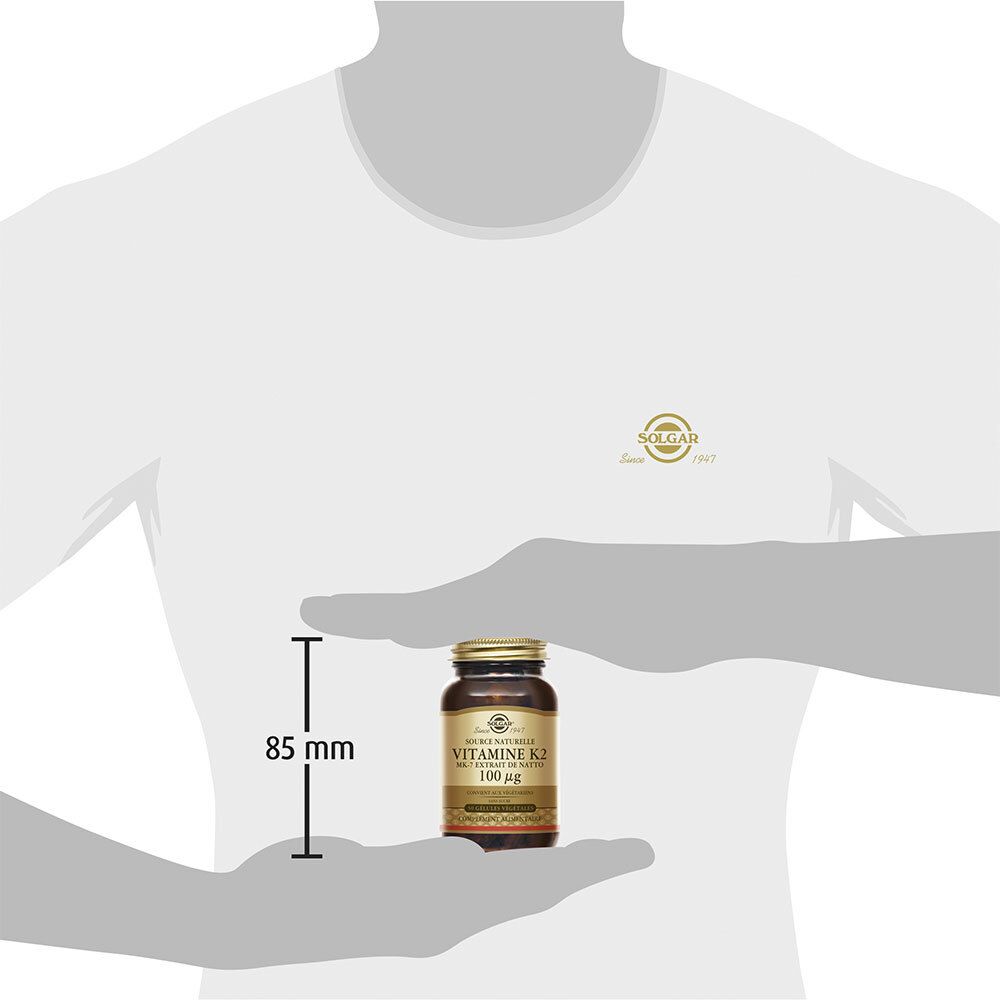 Person hält Flasche mit Solgar Vitamin K2. 85 mm Messlinie neben der Flasche.