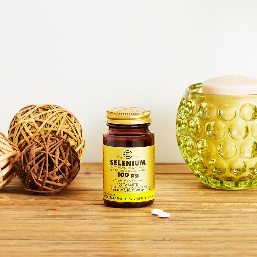 Braune Flasche mit goldfarbenem Deckel auf Holzoberfläche. Dekoration: Kugeln und Kerzenhalter.