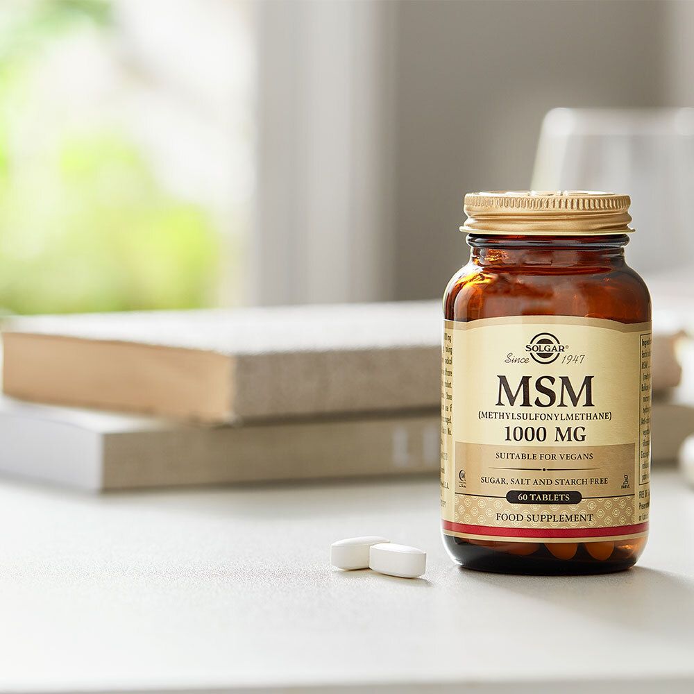 Flasche mit MSM 1000 mg neben Tabletten. Auf Tisch mit Büchern. Marke Solgar, 60 Tabletten.