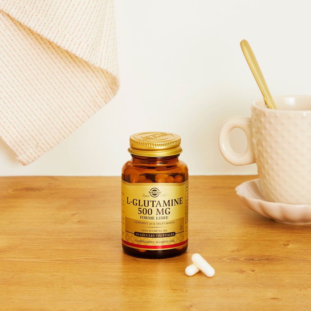 Flacon brun avec gélules sur une table. À côté, une tasse et une cuillère. Fond clair.