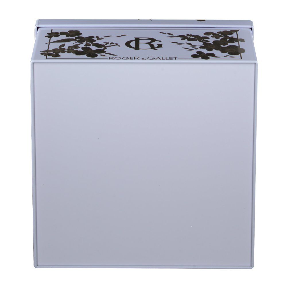 Weiße Schachtel mit goldenen Blumenmustern und dem Markennamen. Die Schachtel ist quadratisch und hat einen Deckel.