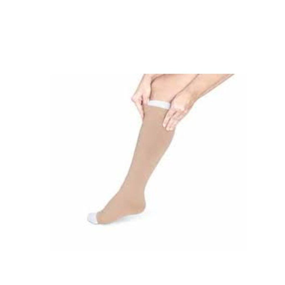 Bas de compression beige sur une jambe. Une personne tire le bas. Bord supérieur blanc.