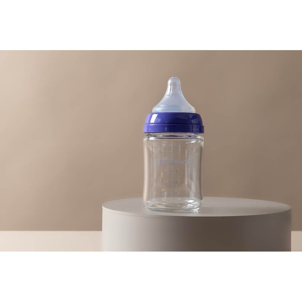 Leere Glasflasche mit blauer Kappe und Sauger, mit Markierungen.