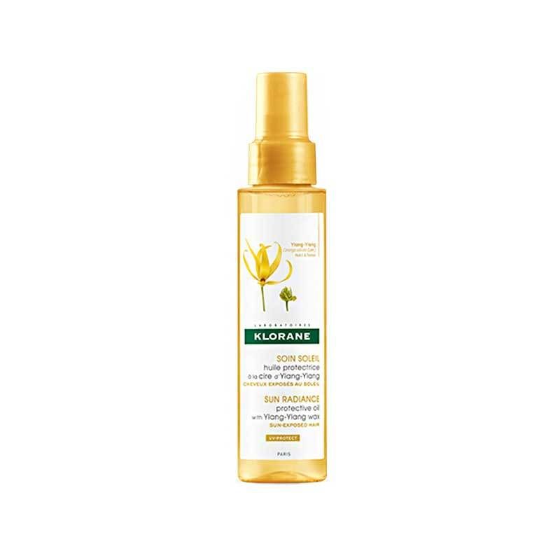 Gelbe Sprühflasche mit goldfarbenem Verschluss. Etikett mit Produktnamen und floraler Illustration. Marke: KLORANE.