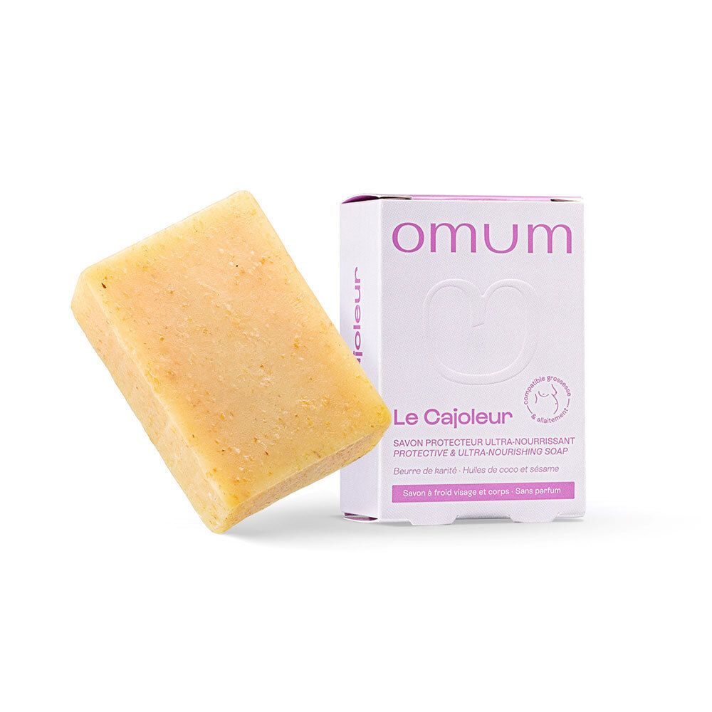 Savon jaunâtre à côté d'un emballage blanc. Emballage avec nom du produit et marque : omum. Savon visage et corps.