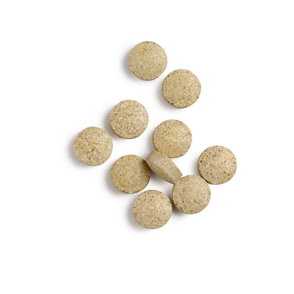 Comprimés ronds beiges sur fond blanc. Quelques comprimés sont dispersés. Pas d'emballage visible.