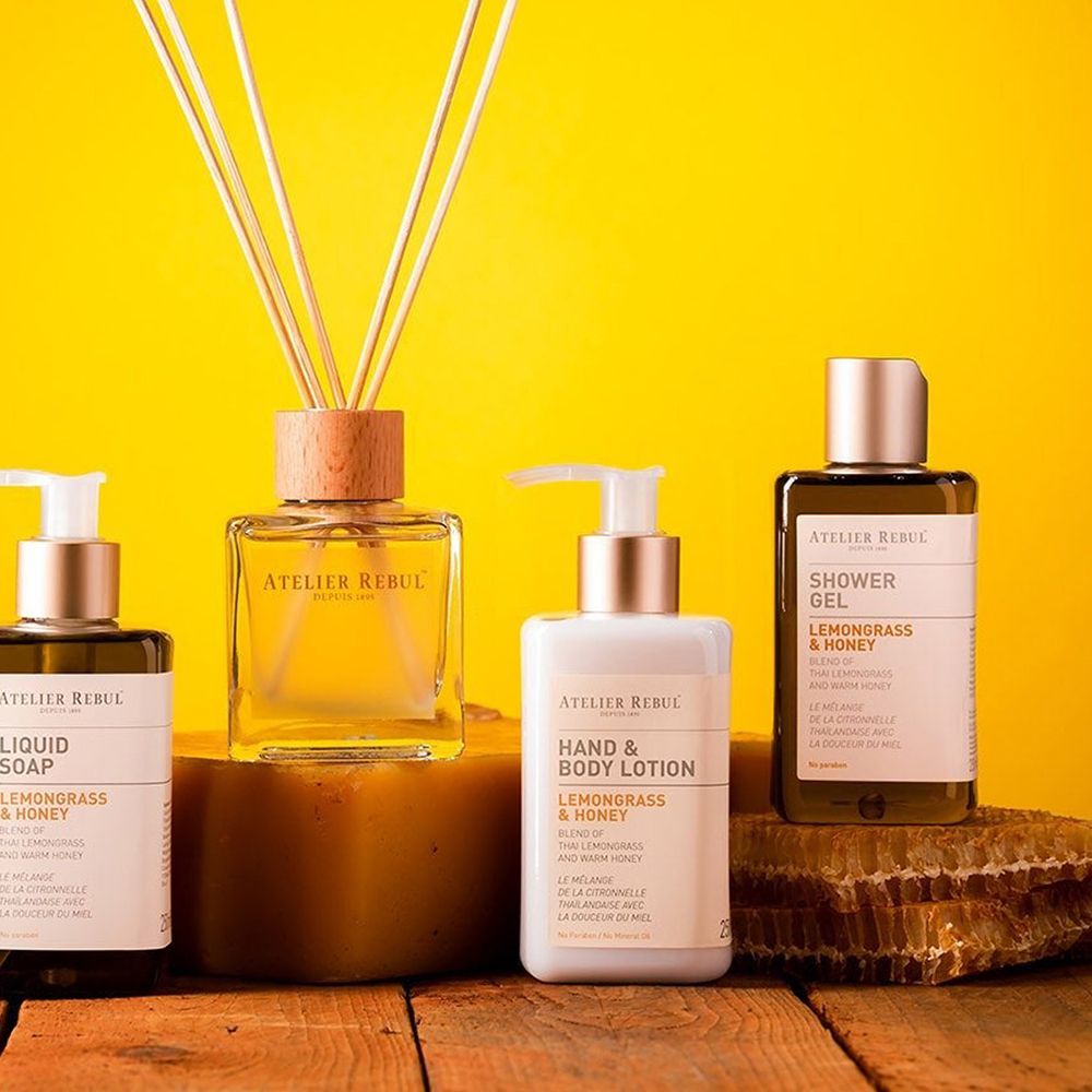 Gamme de produits avec lotion pour les mains et le corps, savon liquide, gel douche et diffuseur de parfum. Sur fond jaune, sur bois et nid d'abeille.