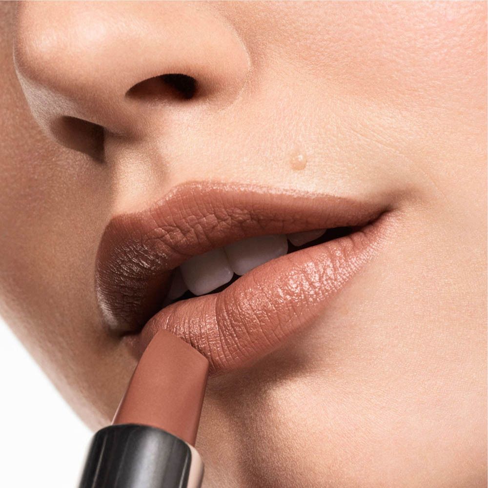 Lippenstift in neutralem Braunton wird auf die Lippen aufgetragen.