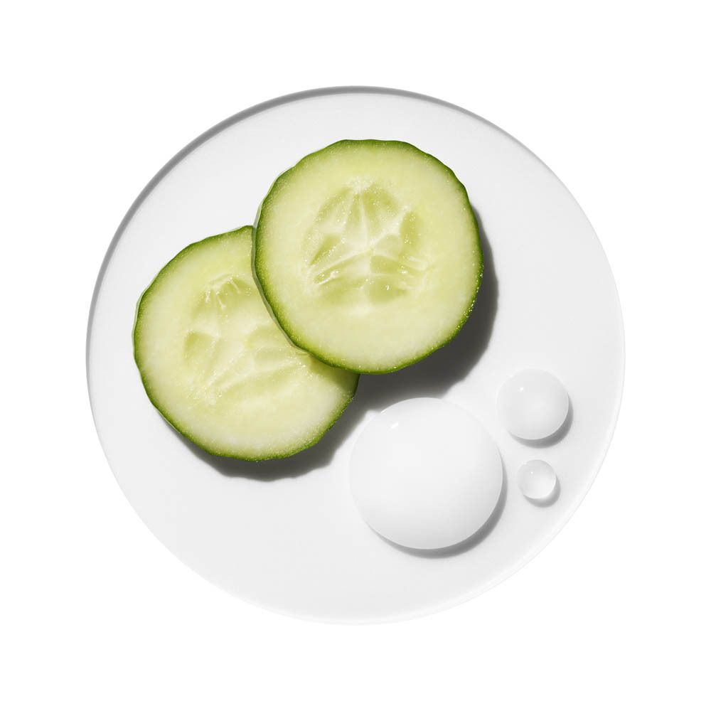 Zwei Gurkenscheiben und drei Tropfen weißer Creme auf weißer Oberfläche.