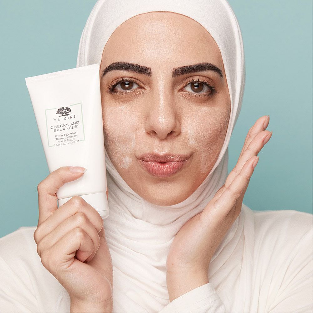 Frau mit Produkt in der Hand. Text: ORIGINS, CHECKS AND BALANCES, Frothy Face Wash.