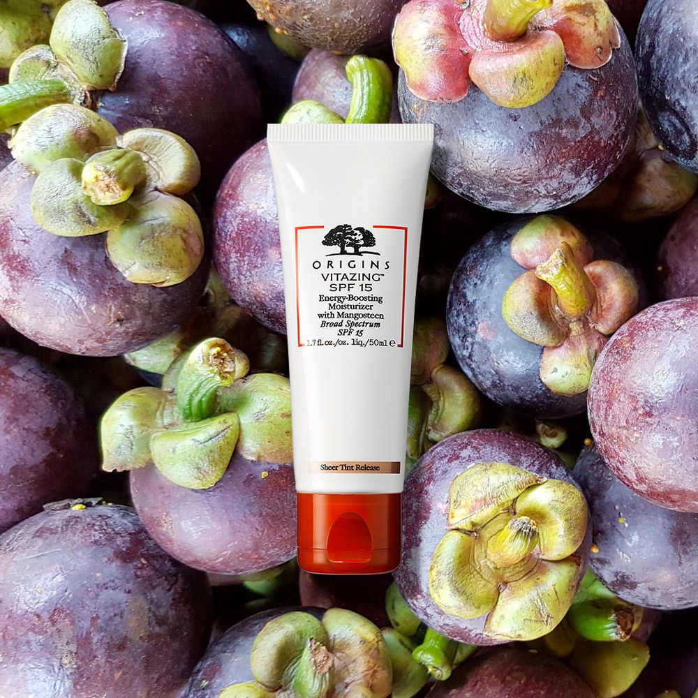 Weiße Tube mit rotem Akzent, umgeben von Mangostan-Früchten. Aufdruck: ORIGINS VITAZING SPF 15.
