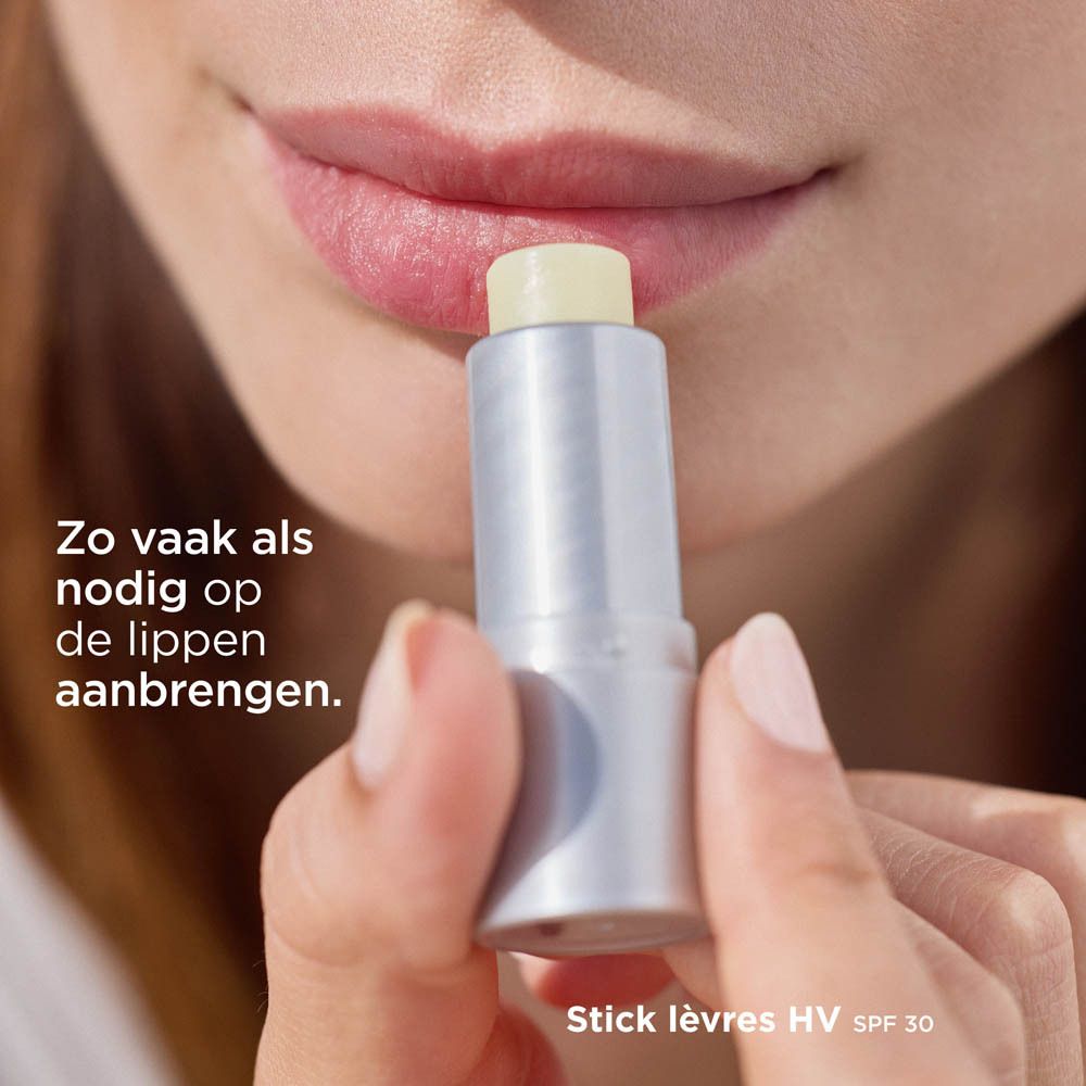 Lèvres enduites avec ISDIN Protector Labial HV LSF 30. Texte: Aussi souvent que nécessaire. Fond bleu.