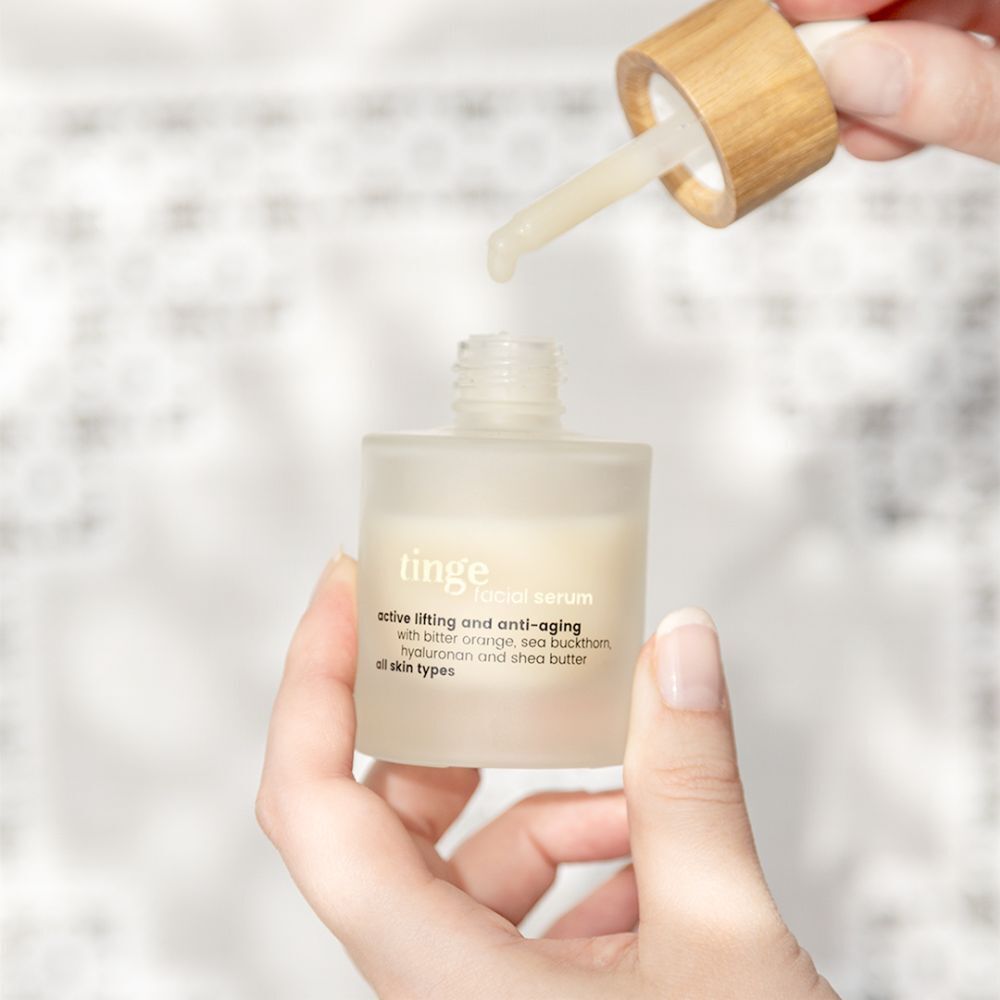 Mains ouvrant un flacon de sérum visage Tinge, la pipette dégoutte.