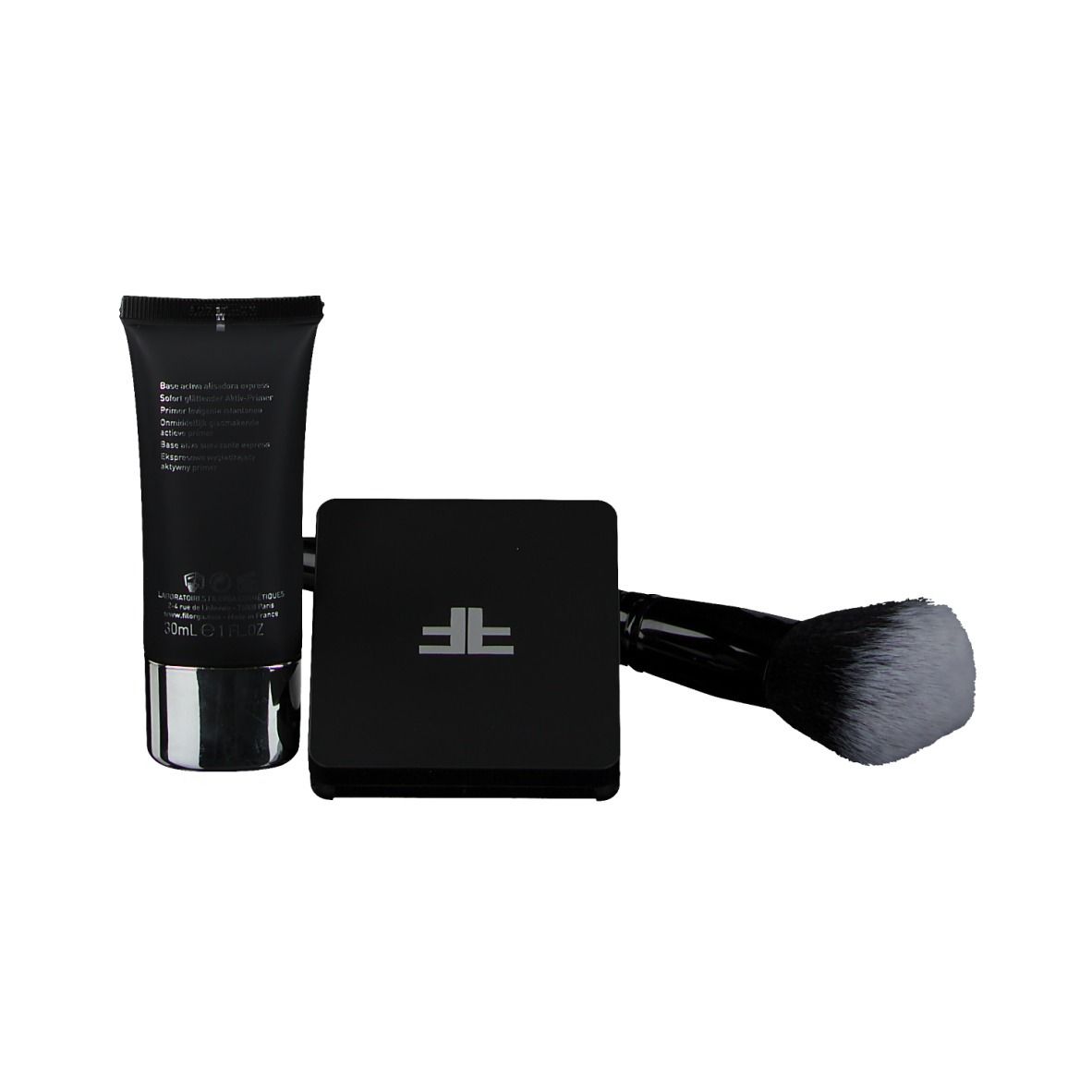 Schwarze Tube, Puder-Kompakt und Pinsel. Tube mit silbernem Boden. Puder in schwarzem Behälter. Pinsel mit schwarzem Griff und Borsten.