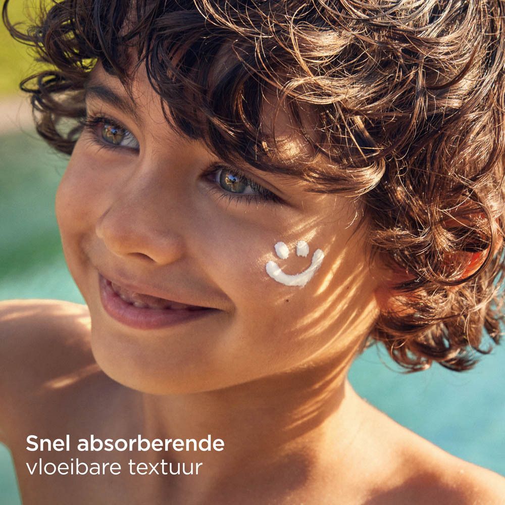 Kind mit Sonnencreme-Smiley auf der Wange. Text: Schnell absorbierende vloeibare textuur.
