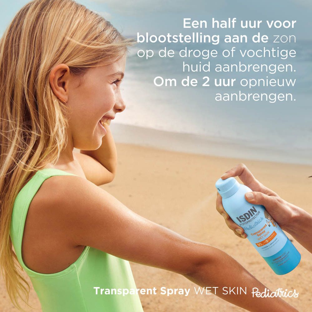 Person sprüht ISDIN Fotoprotector Spray auf die Haut. Blaue Flasche, weißer Deckel. Text auf Niederländisch.