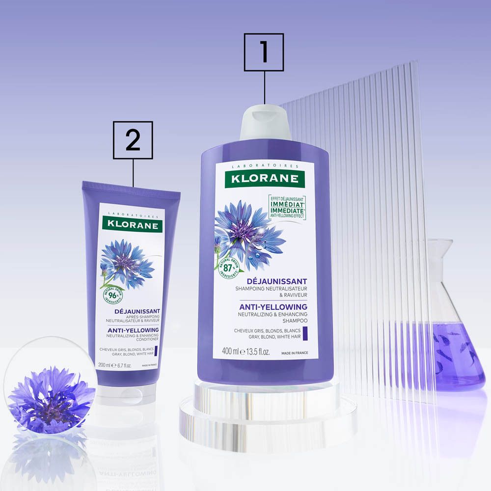 Composition de produits : flacon de shampooing, tube, bleuets. Texte : Klorane, shampooing anti-jaunissement.