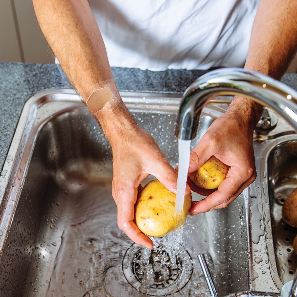 Personne lave des pommes de terre. Pansement Nexcare aqua clear MAXI au poignet.