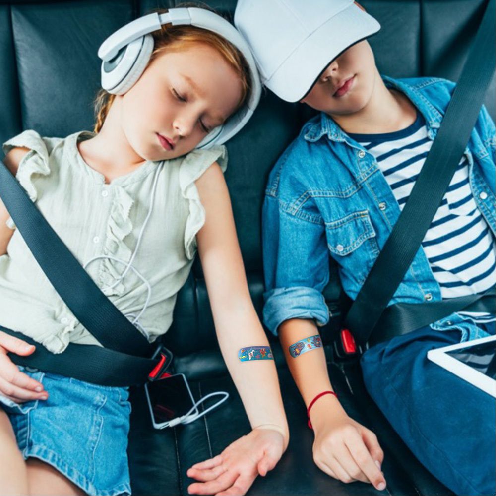 Deux enfants avec des pansements sur les bras. Pansements avec des motifs de bandes dessinées. Enfants attachés dans la voiture.