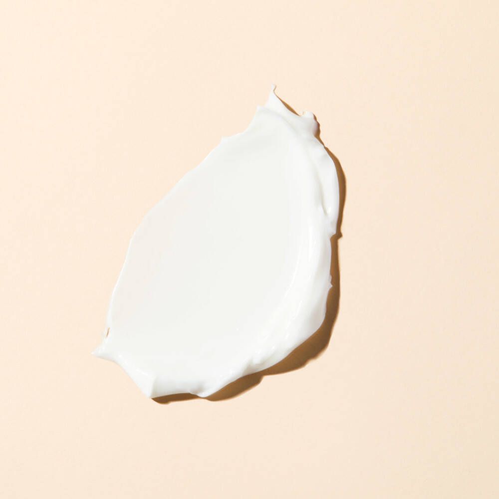 Klecks Creme auf beigem Hintergrund. Weiße Creme, glatt und strukturiert.