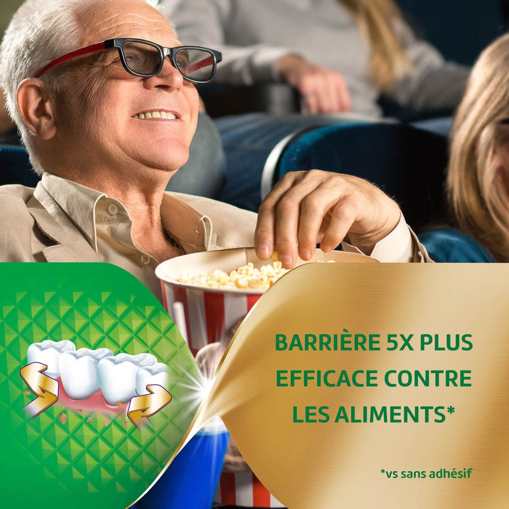Homme au cinéma. Pop-corn. Prothèse dentaire. Texte: BARRRIÈRE 5X PLUS EFFICACE CONTRE LES ALIMENTS.