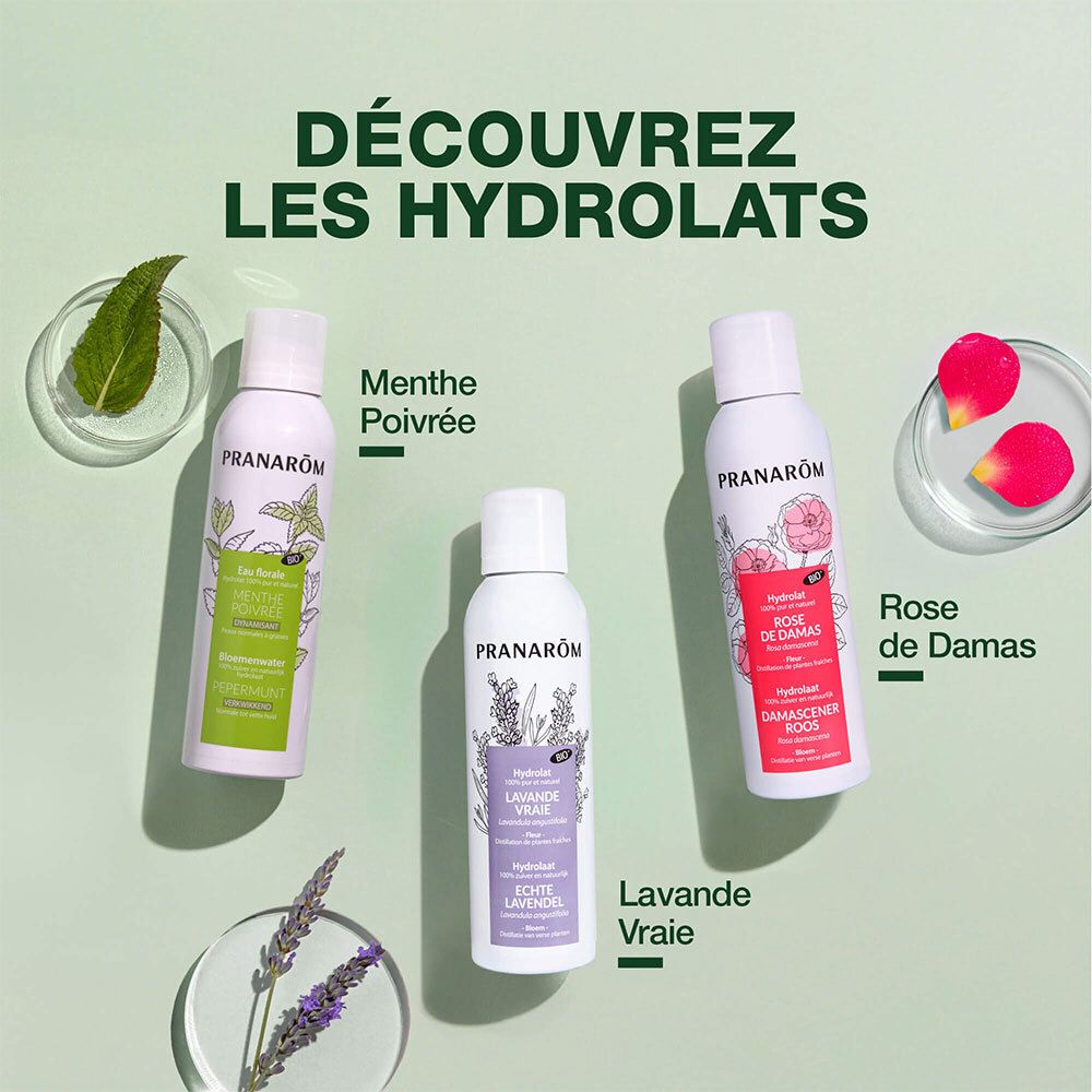Trois flacons Pranarôm: Menthe Poivrée, Lavande Vraie, Rose de Damas. À côté: menthe, fleurs de lavande, pétales de rose.