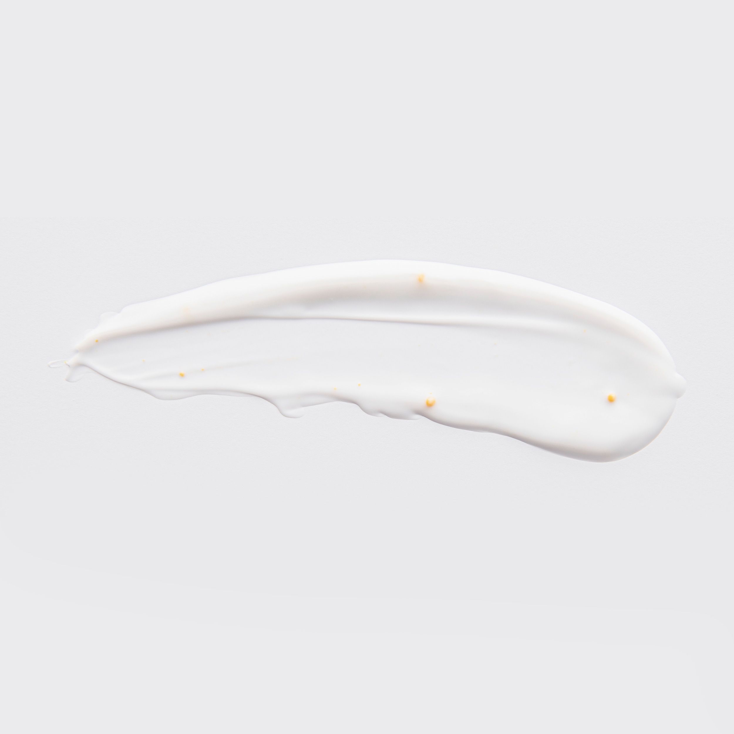 Trait de crème blanche avec perles jaunes Q10. Sur fond clair.