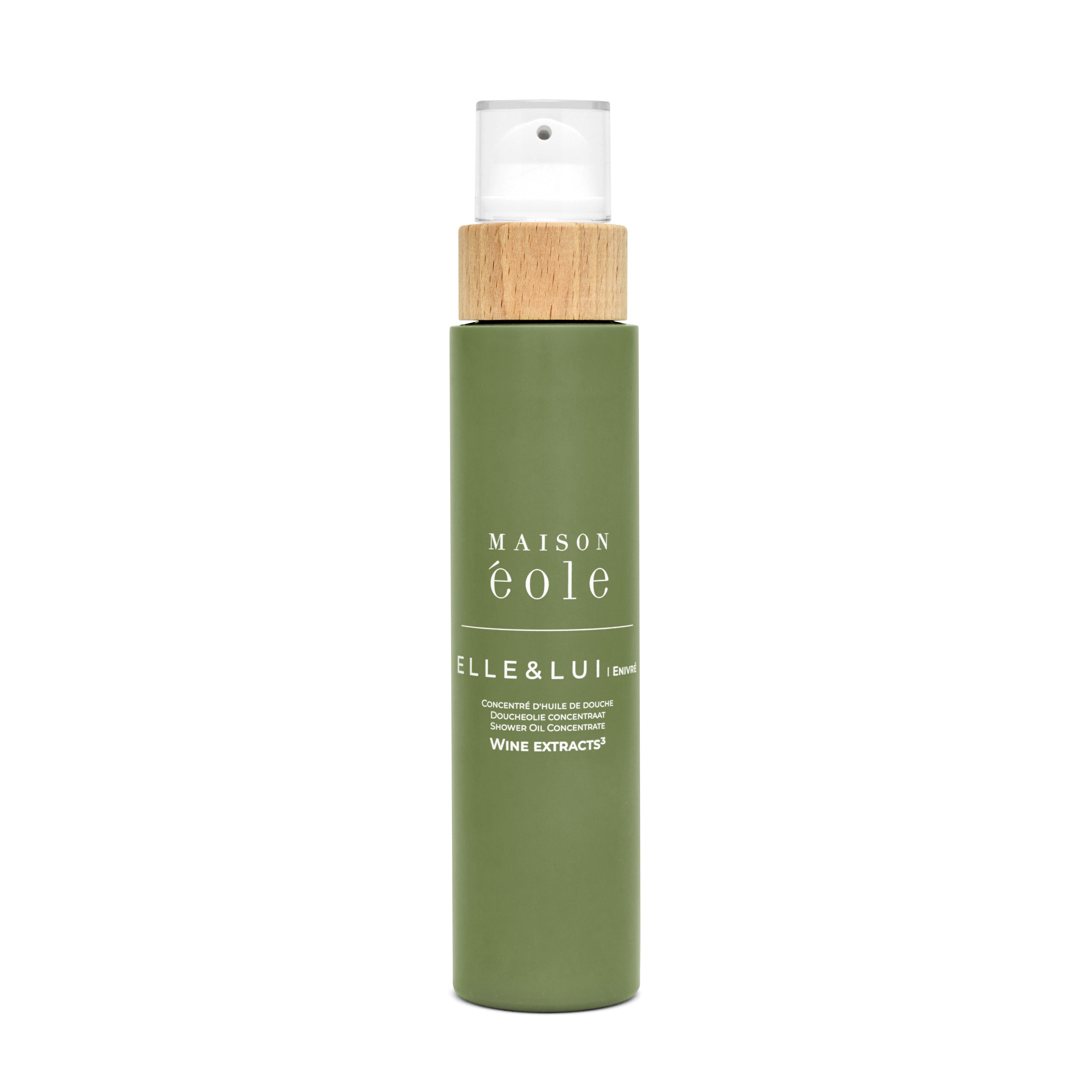 Flacon vert avec bouchon pulvérisateur et couvercle en bois. Inscription: Maison Éole, Elle & Lui, Concentré d'Huile de Douche.