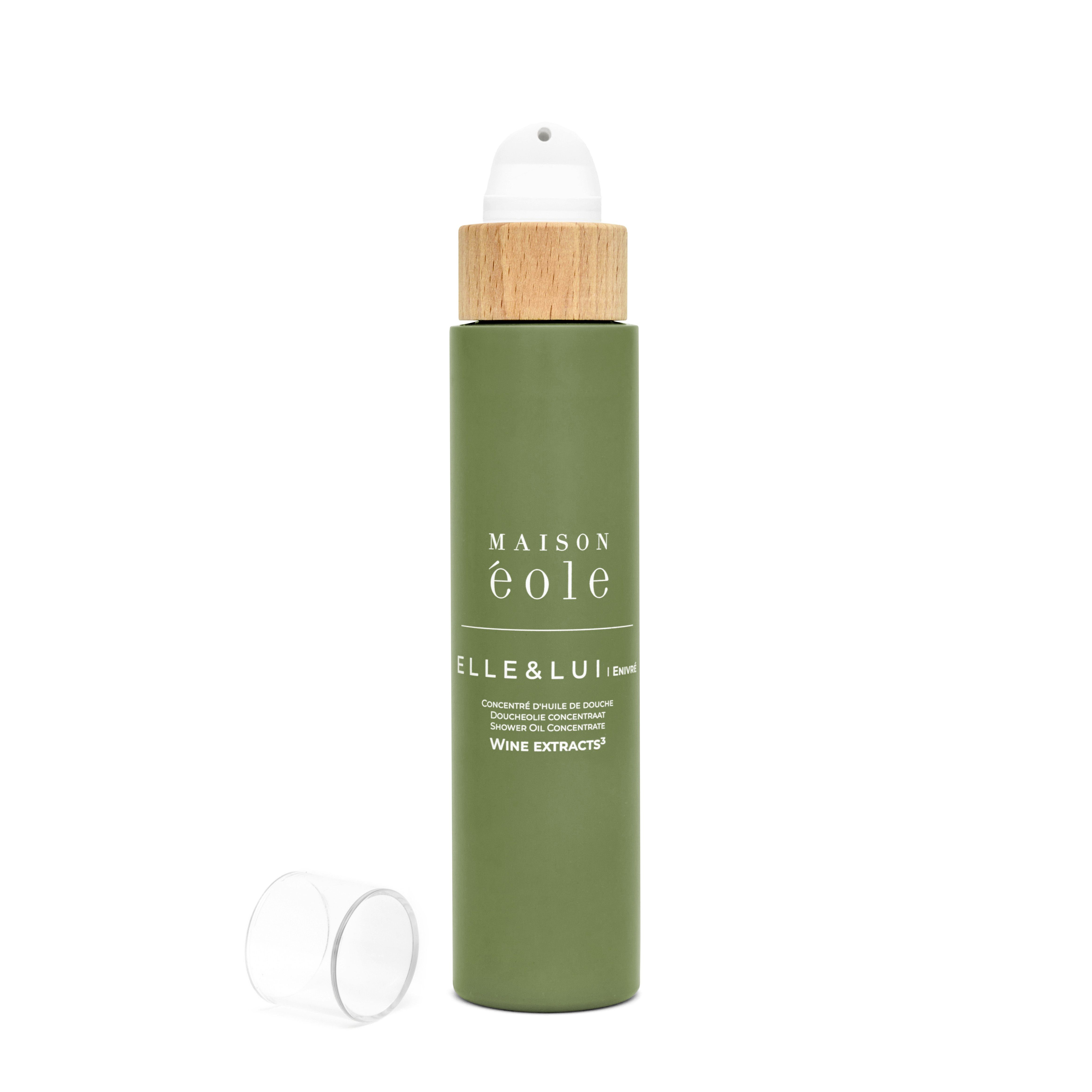 Flacon vert avec bouchon pulvérisateur et couvercle en bois, sans bouchon. Inscription: Maison Éole, Elle & Lui, Concentré d'Huile de Douche.