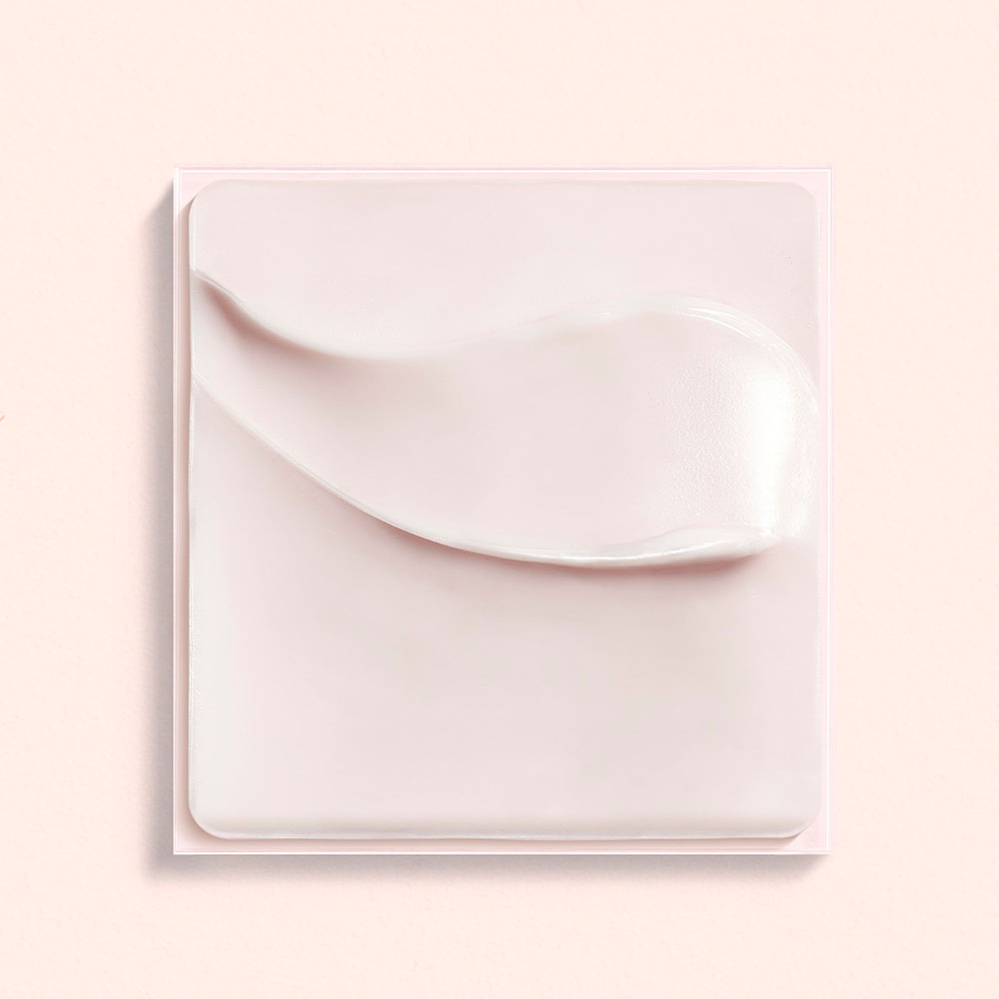 Crème rose sur support carré. Trace de crème visible.