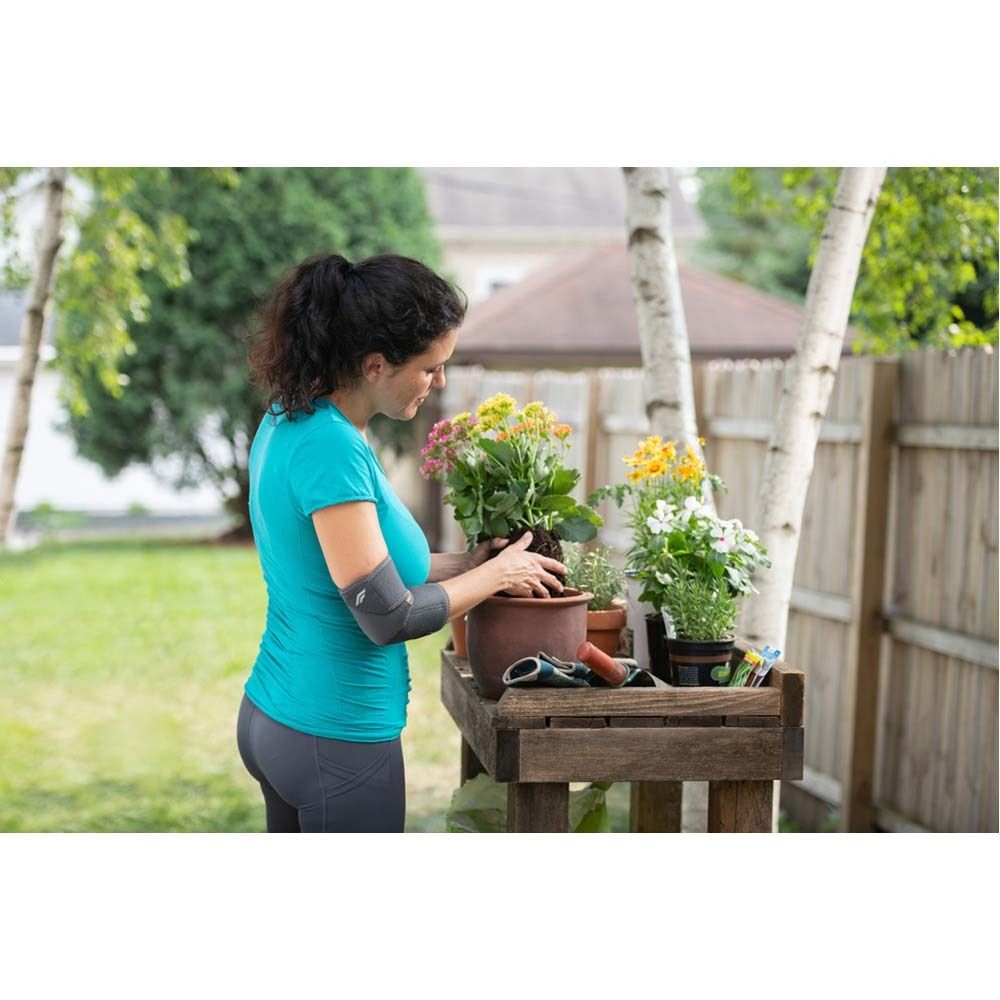 FUTURO™ Ellenbogenbandage, grau. Produktansicht, ohne Verpackung, auf Arm. Flexibles Material, anatomische Form.