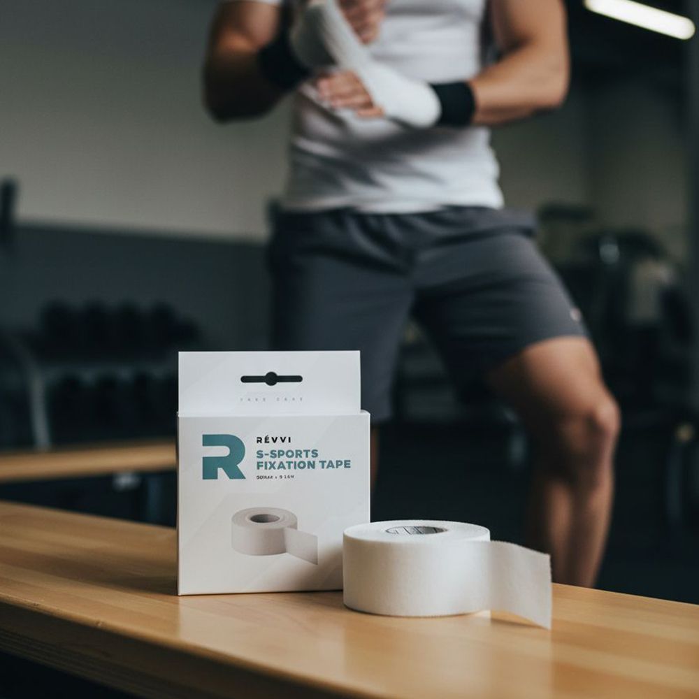 Produktverpackung mit Logo und Aufschrift S-Sports Fixation Tape. Daneben eine Rolle graues Klebeband. Person im Hintergrund mit Bandagen.