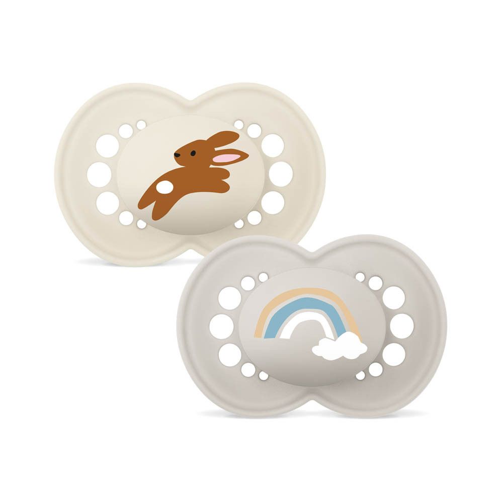Deux sucettes MAM Original Pure (16+ mois). Une beige avec lapin, une beige avec arc-en-ciel.
